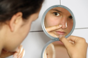 teen looking at their face in the mirror